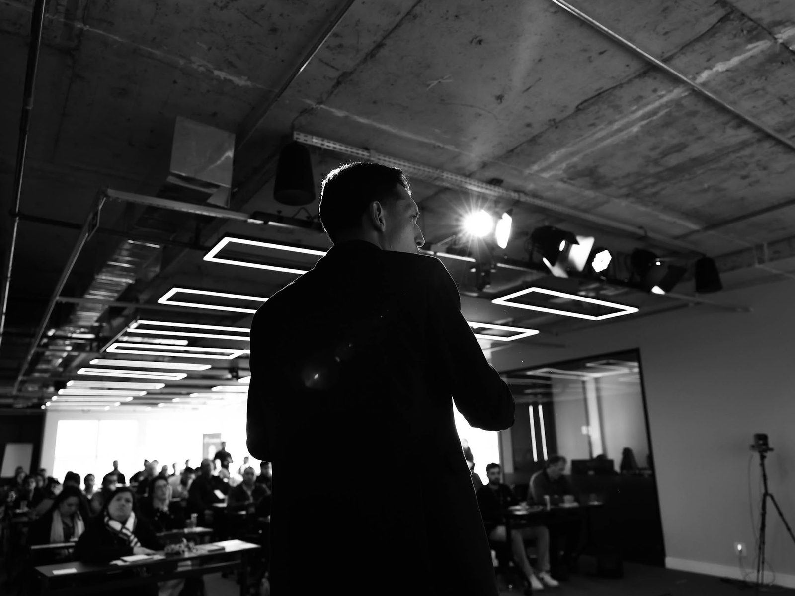 Palestrante no palco sob a iluminação cênica do auditório